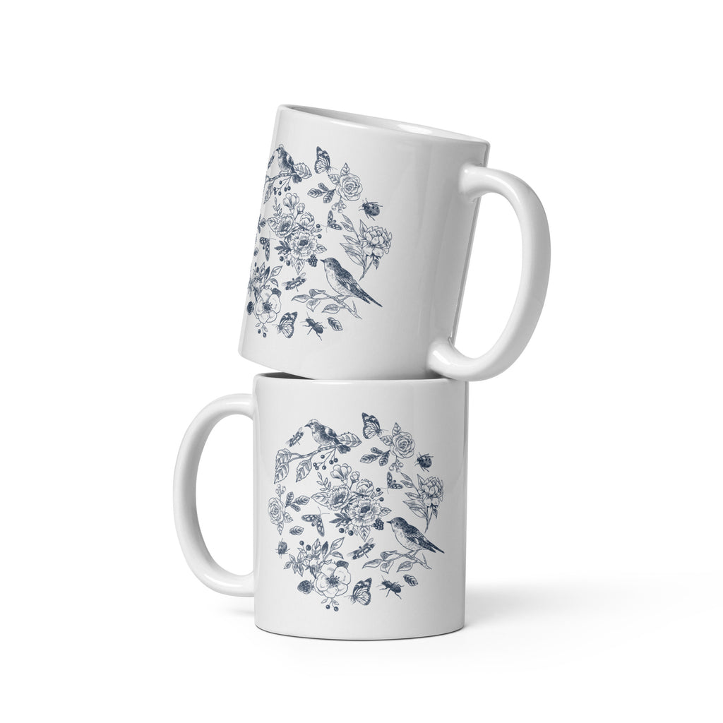 two 11 ounce white mug with a design in blue featuring a variety of birds, garden plants and insects